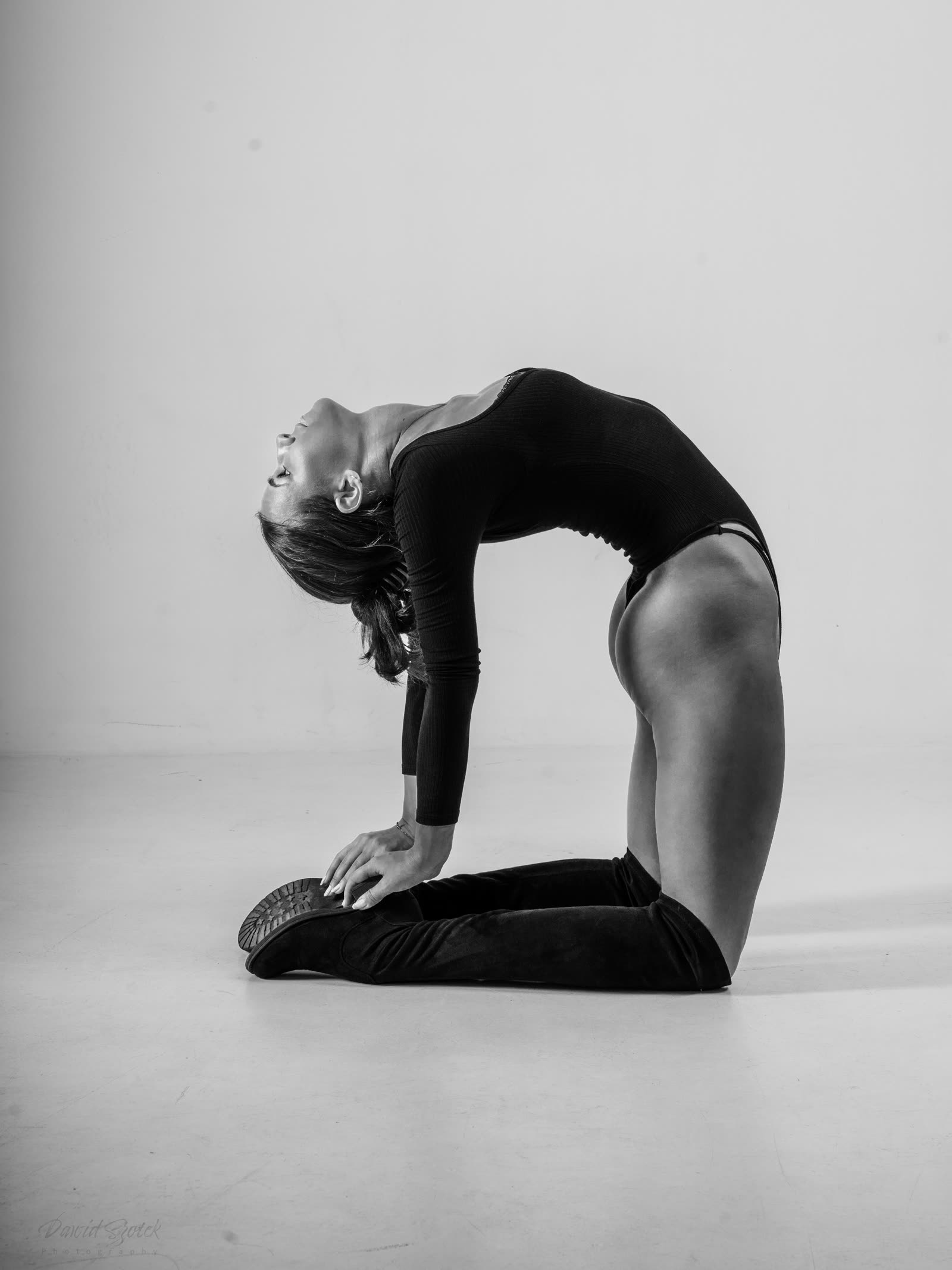 Czarno-biała sesja portretowa — kobieta w pozie camel pose, studio fotograficzne Kraków