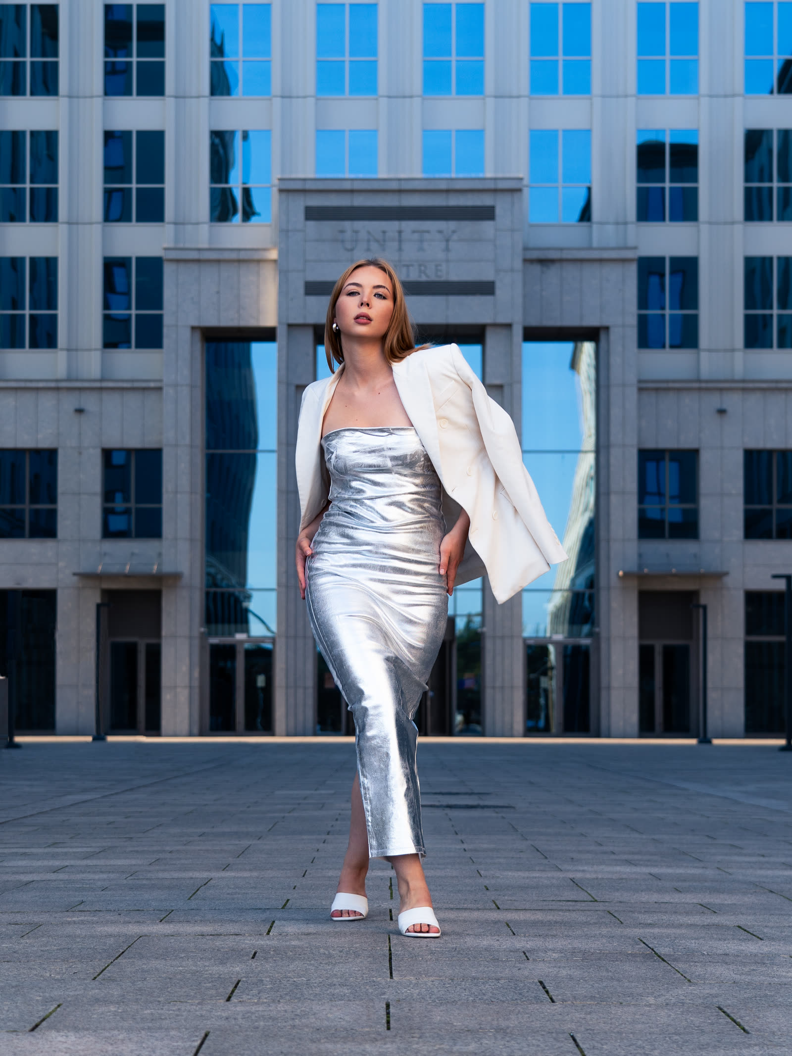 Sesja fashion editorial w Krakowie — kobieta w srebrnej sukience przed bryłą Unity Centre, fotograf Dawid Szotek