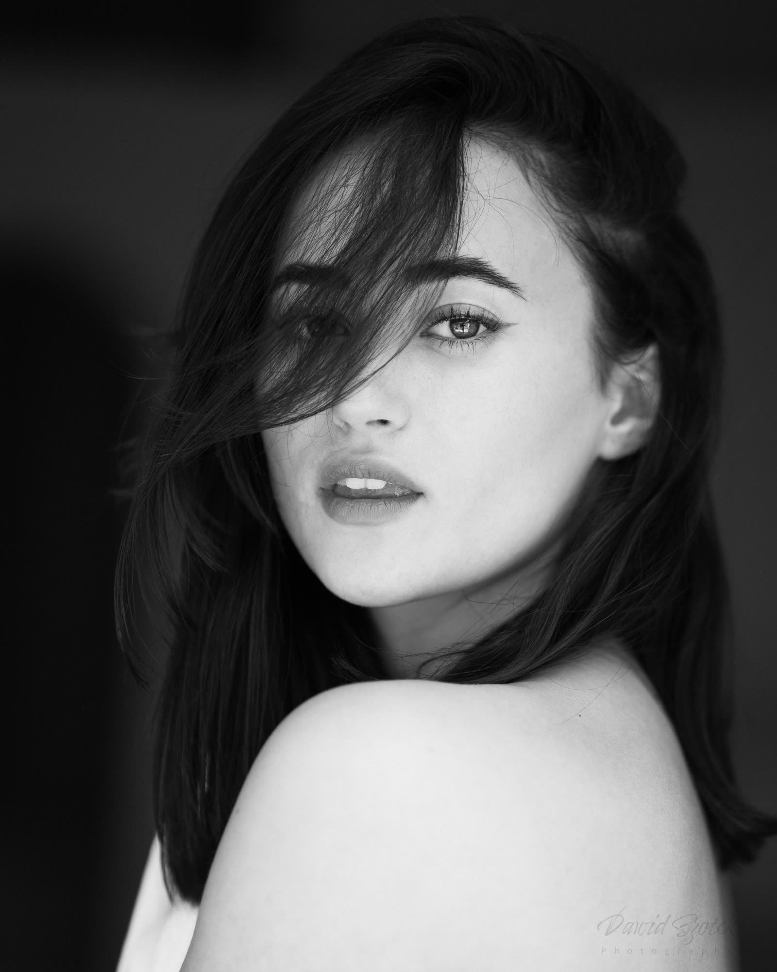 Czarno-biały portret kobiecy — intymny gaze, włosy opadające na twarz, fine art photography Kraków